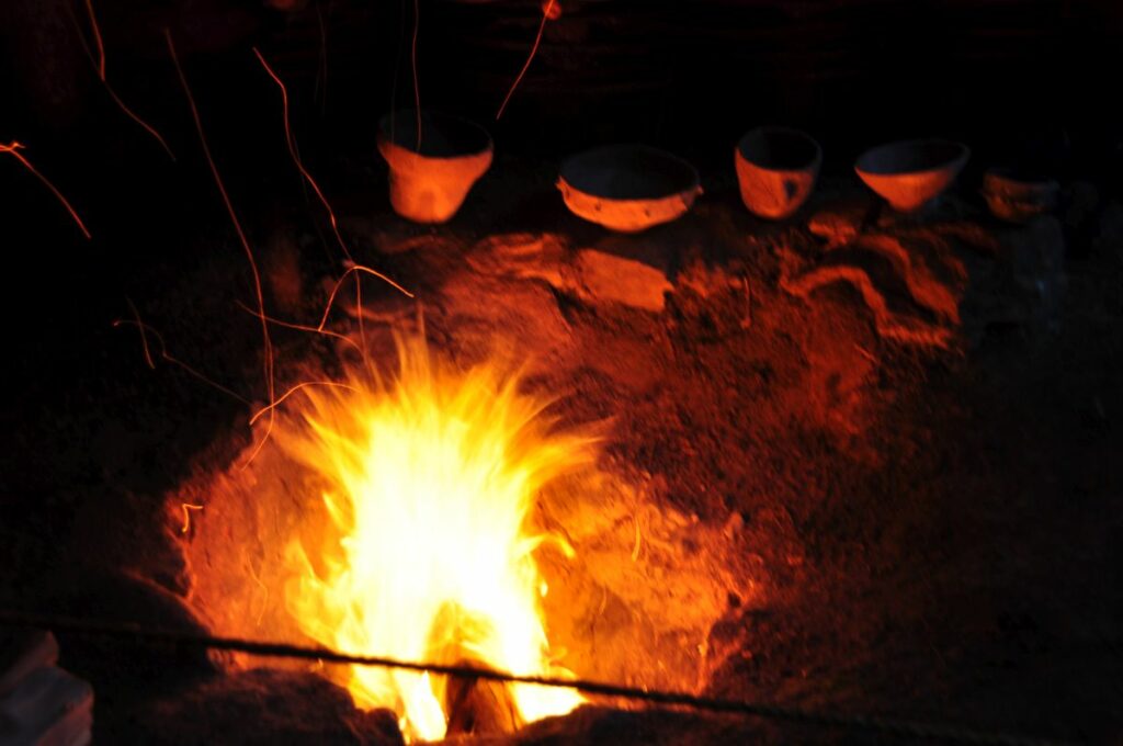 Vorführung zum jungsteinzeitlichen Keramikbrand im archeoParc Schnalstal<br/>Dimostrazione della cottura della ceramica in maniera preistorica allarcheoParc Val Senales<br/>Demonstration of prehistoric pottery firing in a pit at archeoParc Val Senales