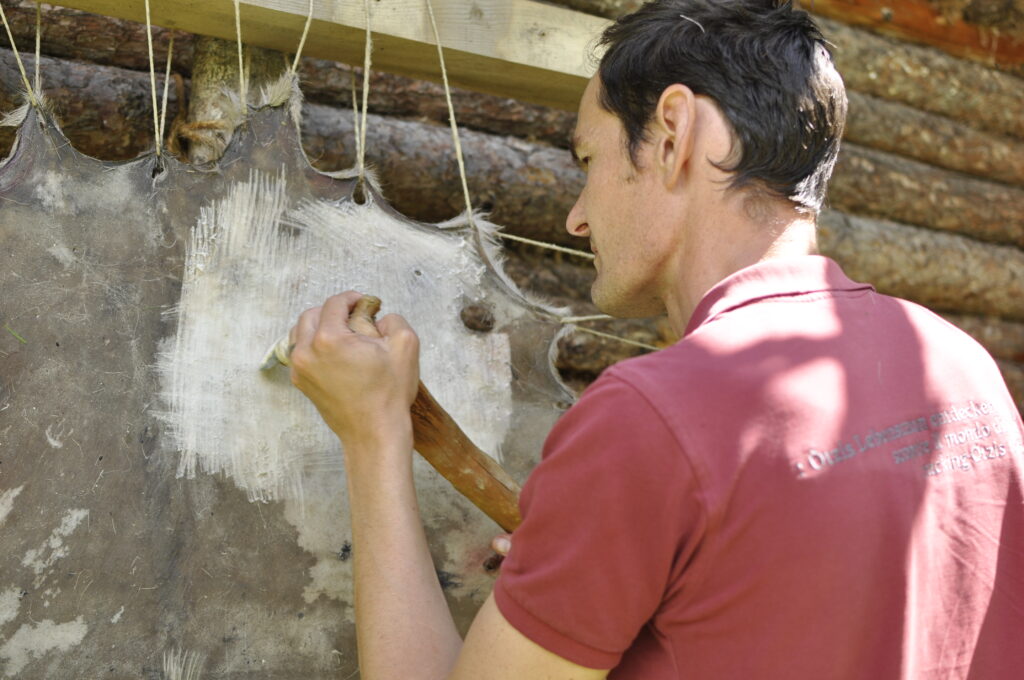 Handwerksdemonstration zum steinzeitlichen Gerben im archeoParc Schnalstal<br/> Dimostrazione sulla conciatura in maniera di Ötzi all’archeoParc della Val Senales<br/>Demonstration on neolithic tanning at archeoParc Val Senales archeological open air museum